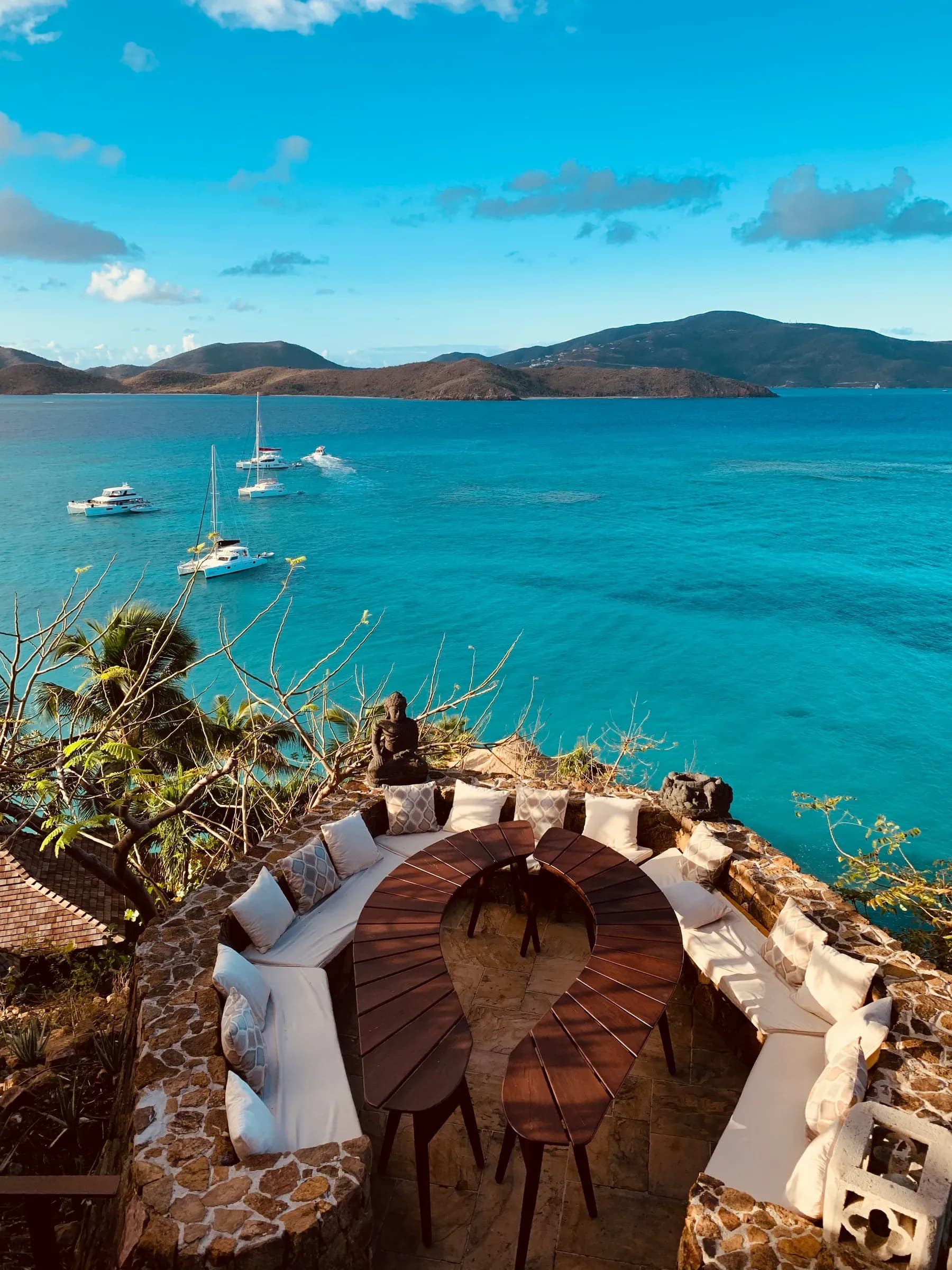 A stone terrace with cushioned seating above a bay of moored yachts