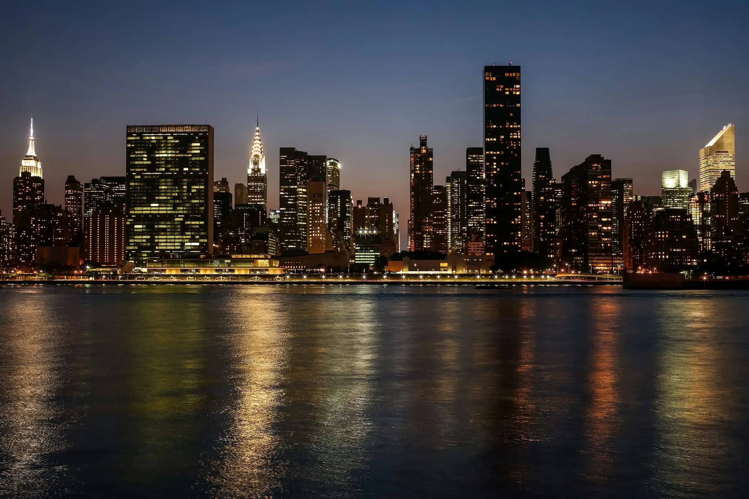 A city skyline lit up at night across dark water
