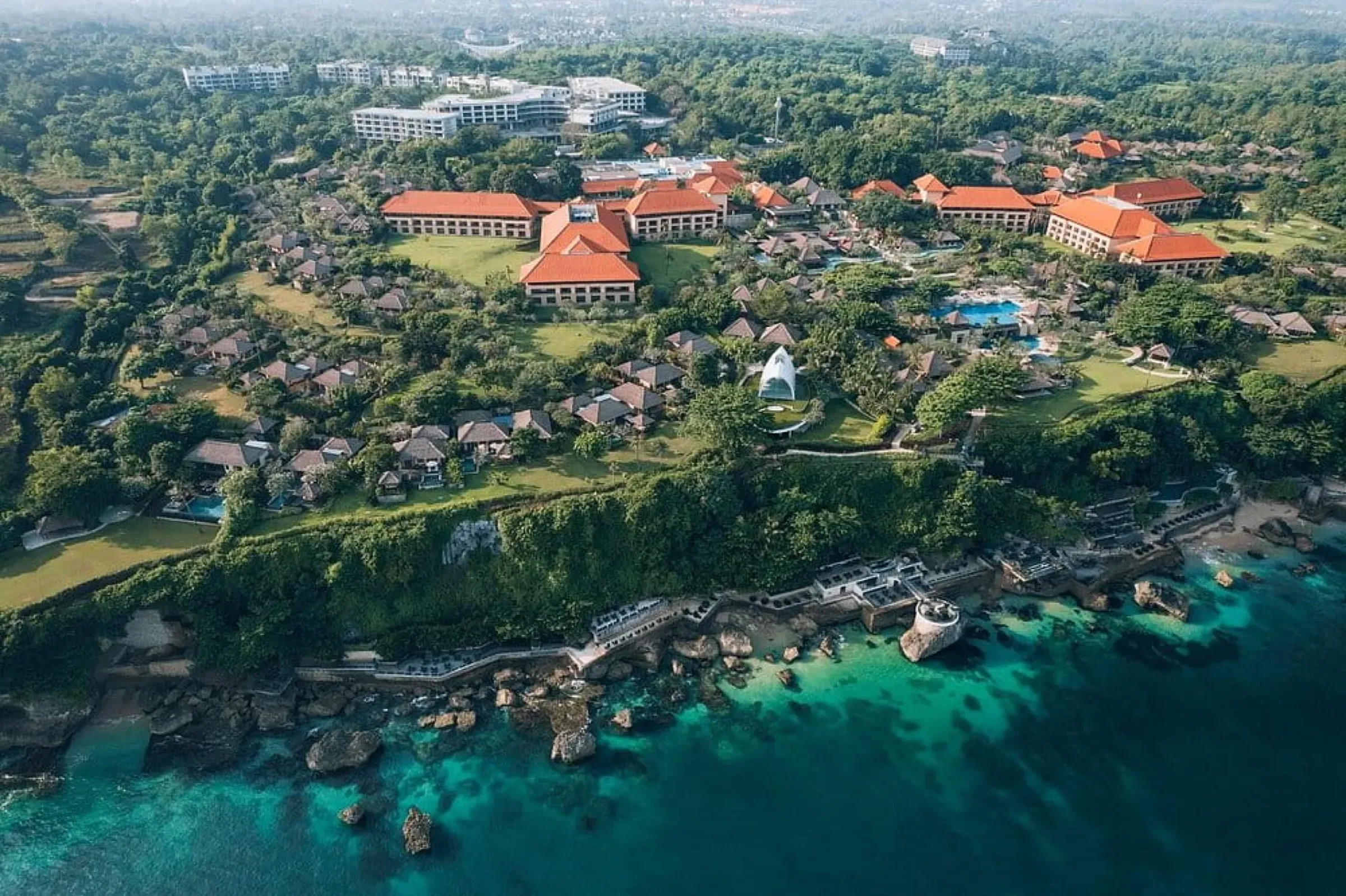 An aerial view of a clifftop resort above a reef and turquoise sea