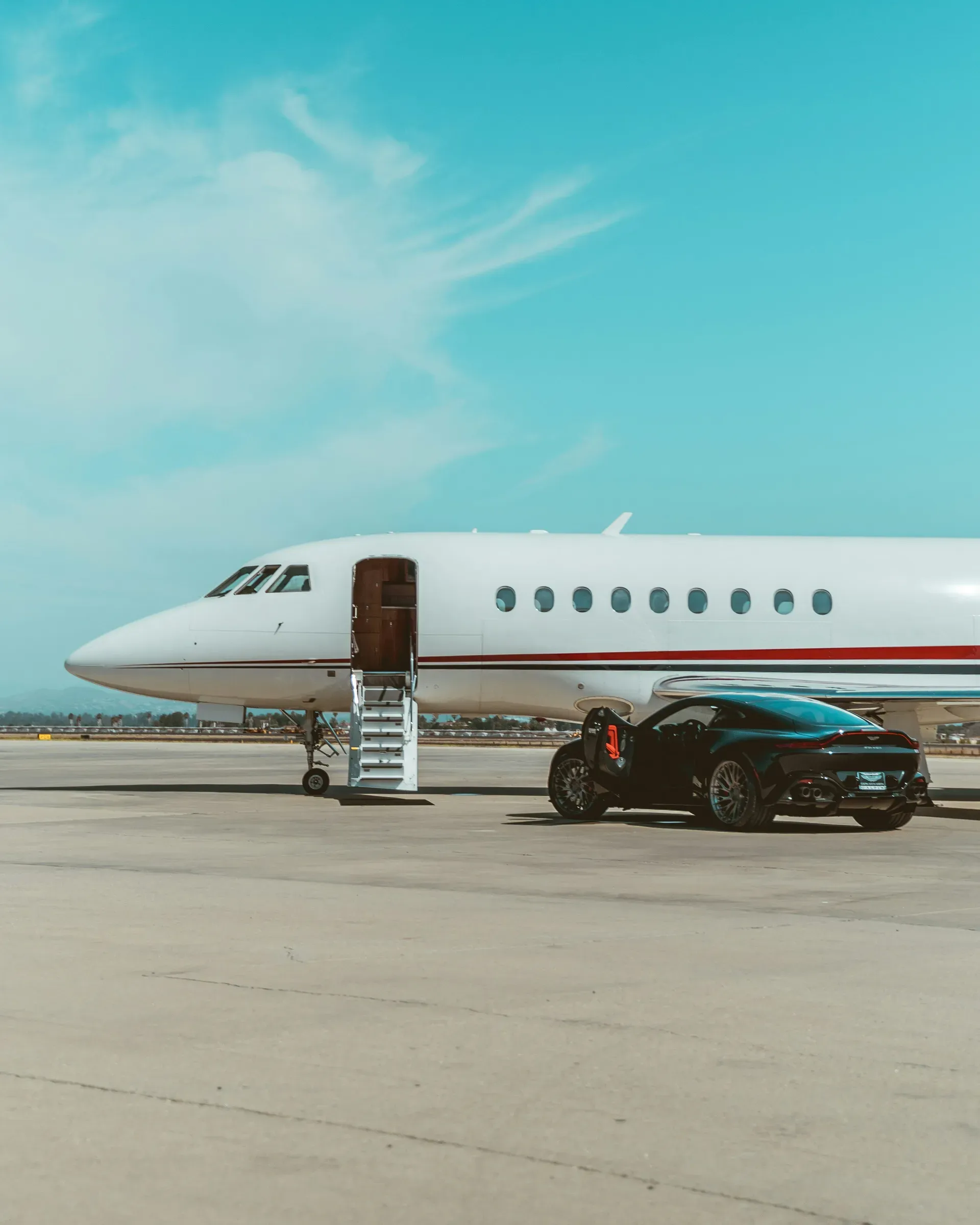 A private jet on the apron with a black car parked by its stairs