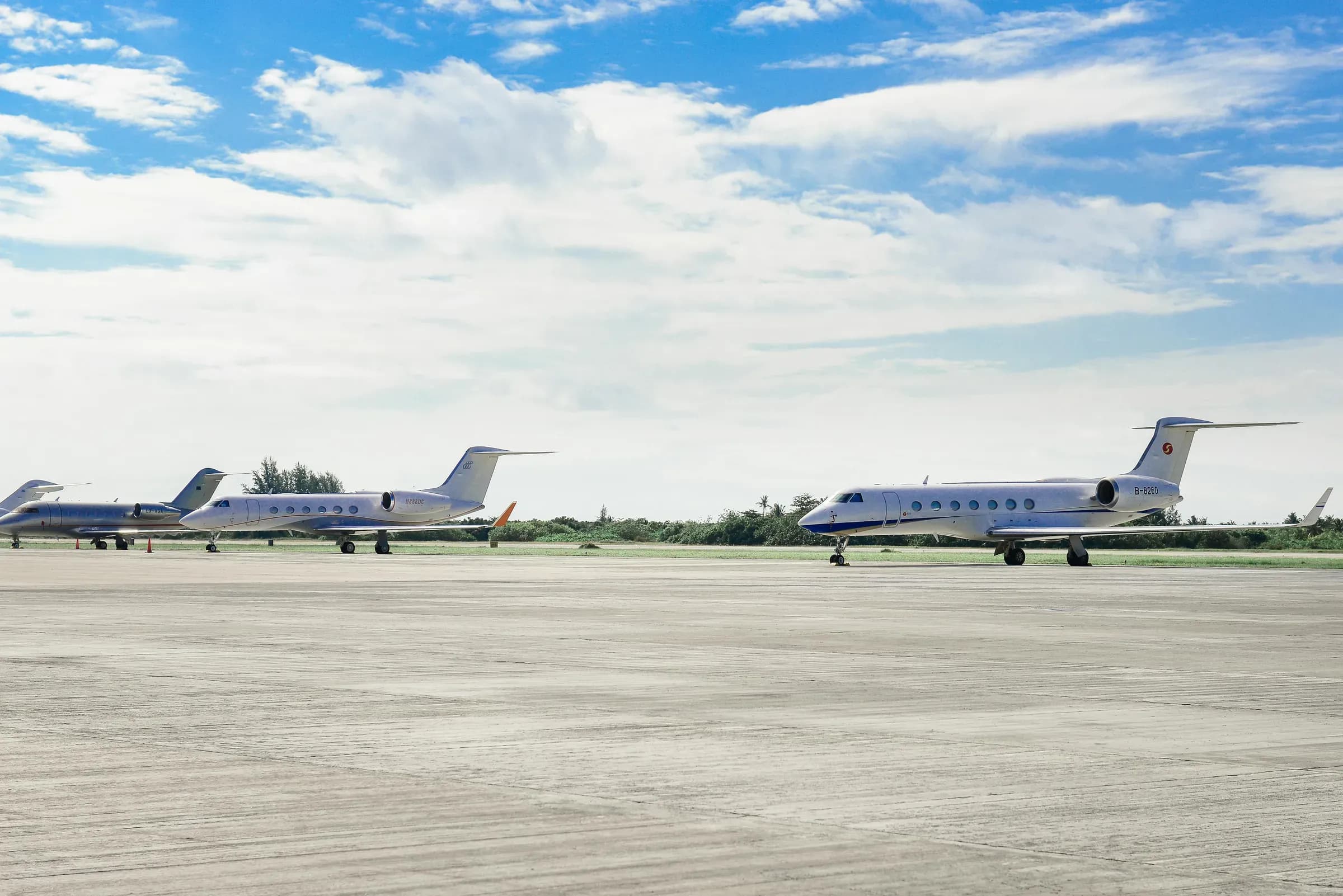 Private jets parked in a row on an open apron