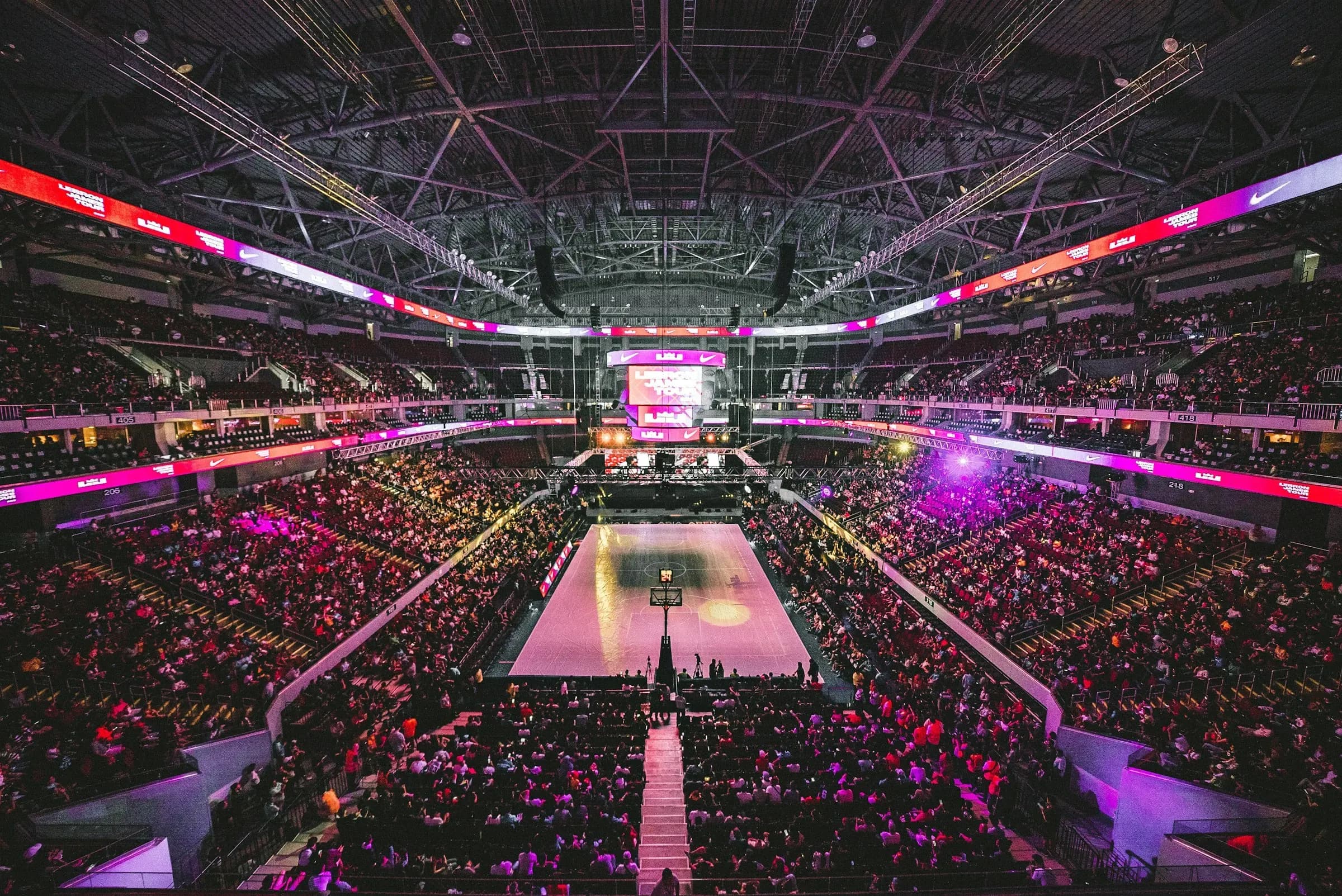 A packed indoor arena around a lit court, seen from high above